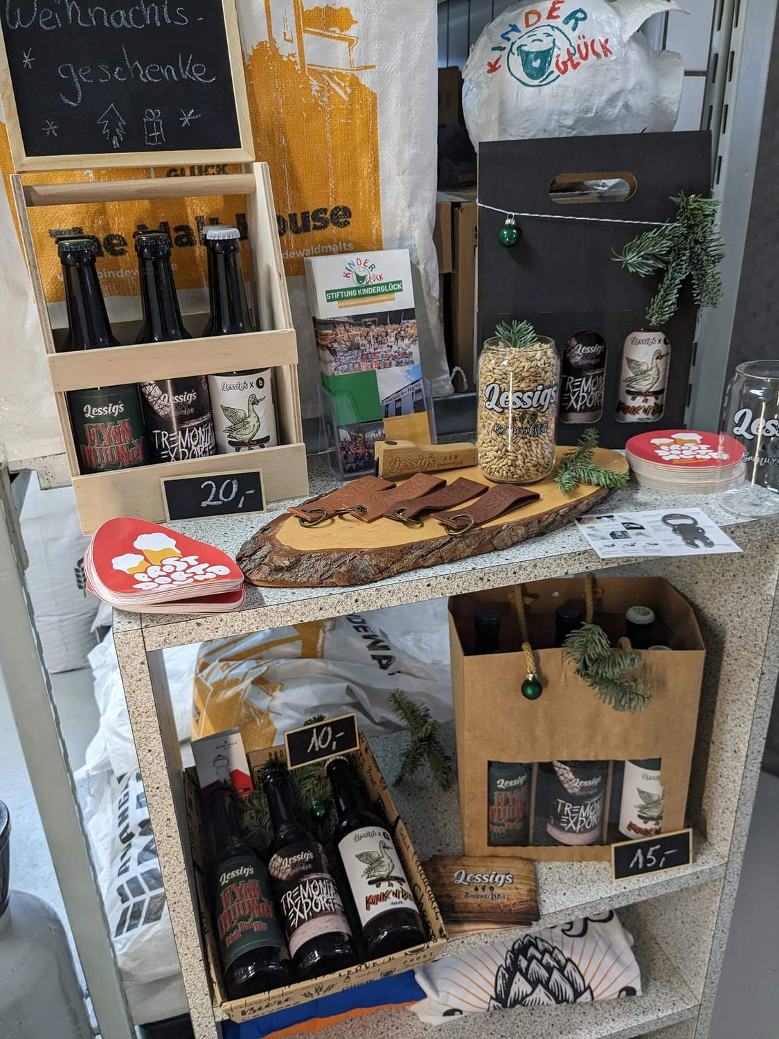 Lessigs Brauwerkstatt GmbH – Dieses Bild zeigt eine Ausstellung handwerklich hergestellter lokaler Produkte und Geschenksets, darunter Flaschenbier von „Lessig’s“ und andere Gourmetartikel.